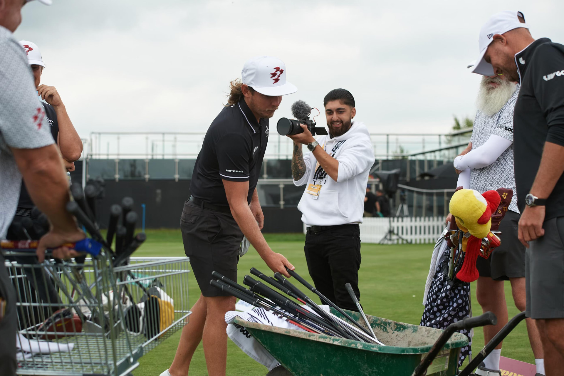 IHM videographer filming a player selecting clubs on the range at a LIV Golf event